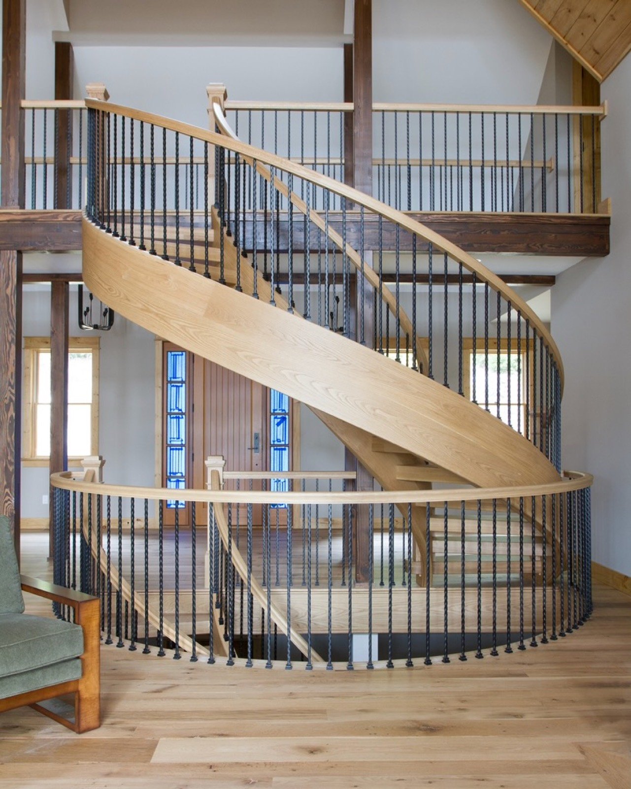 Sweeping contemporary staircase with curved pale wood stringer and black balusters